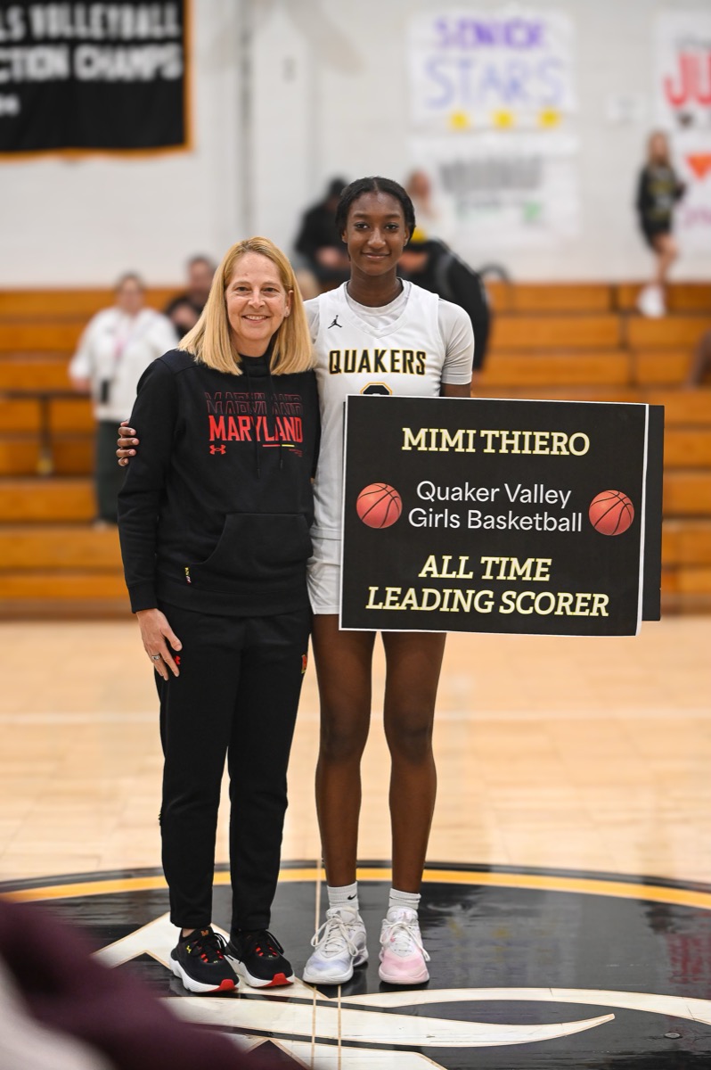 Mimi Thiero holding the all-time leading scorer sign at center court