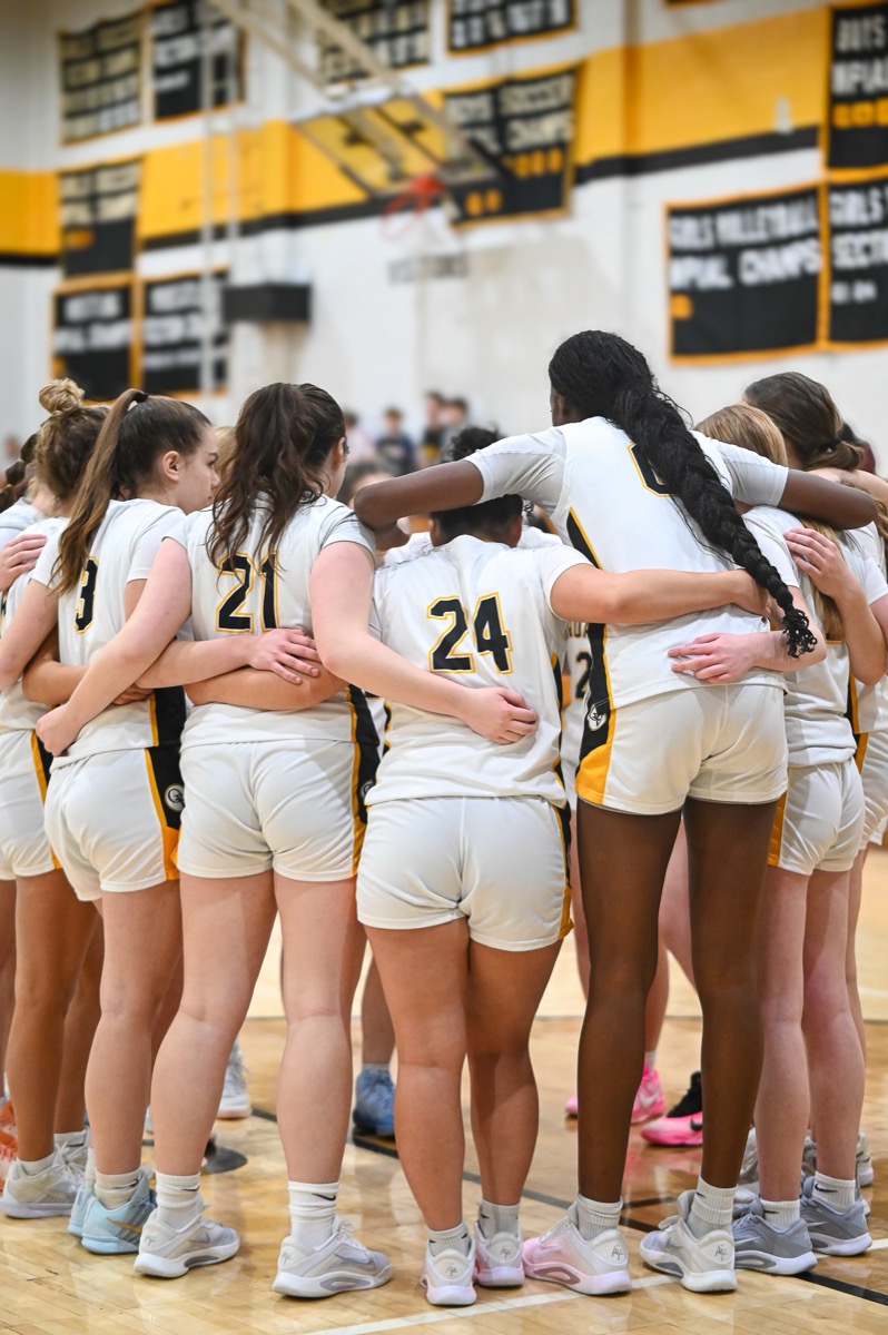 QV Girls Basketball team in a huddle on the court during Senior Night